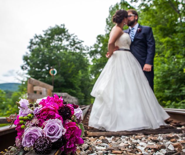 Wedding bouquet and couple kissing on tracks