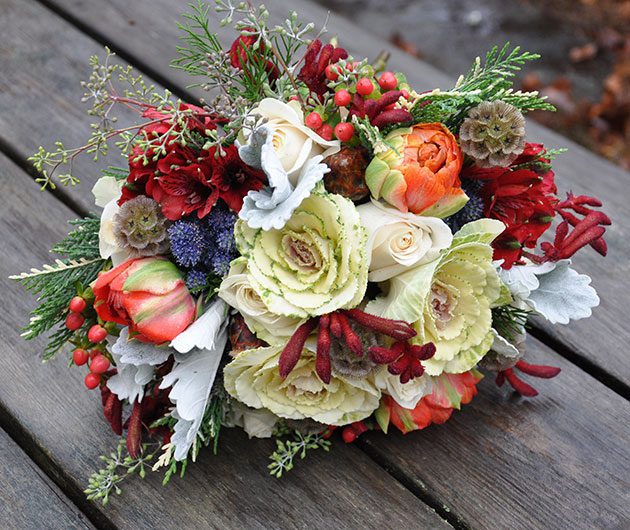 Rustic bouquet with roses, ranunculus, red berries