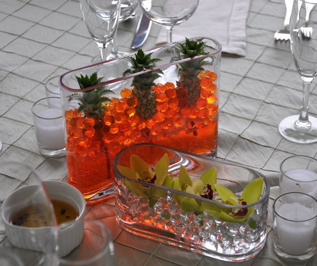 Glass centerpieces with orange beads and orchids