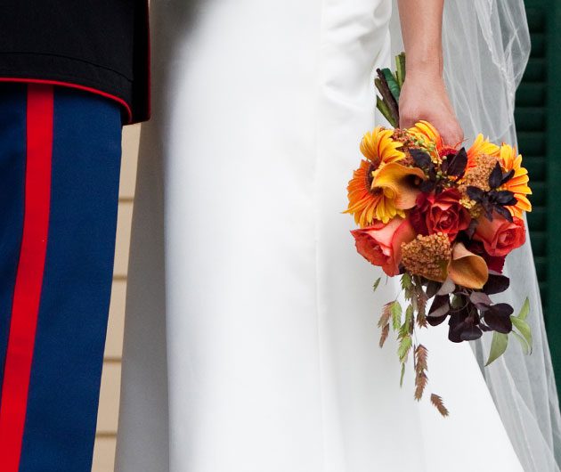 Bride holding autumn bouquet beside uniformed groom