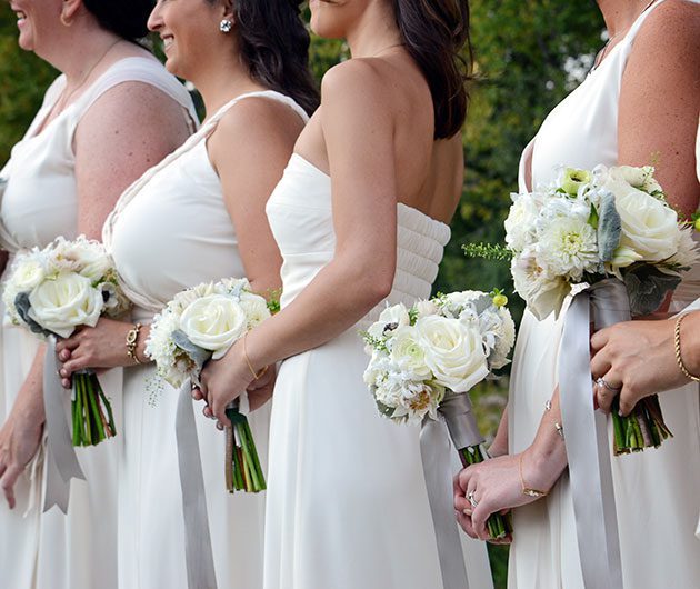 Bridesmaids in white dresses holding white bouquets
