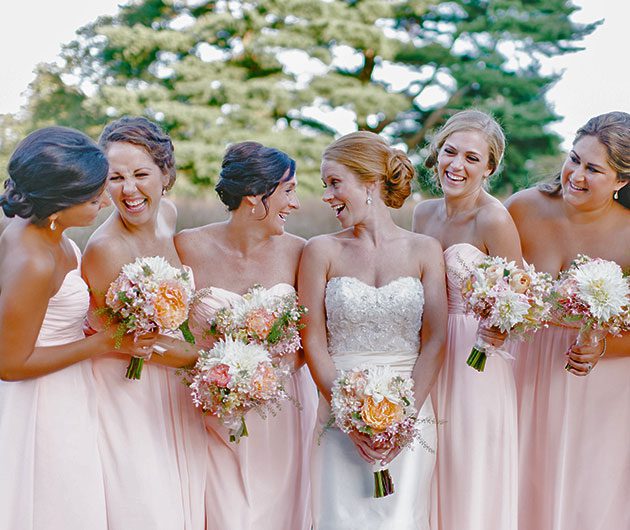 Bride and bridesmaids laughing, holding bouquets