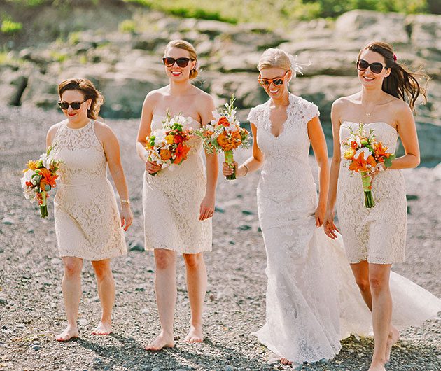 Bride and three bridesmaids walking on beach