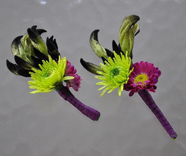 Green and magenta floral boutonnieres with feathers