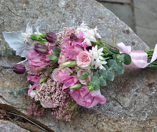 Pink floral bouquet with ribbon on stone