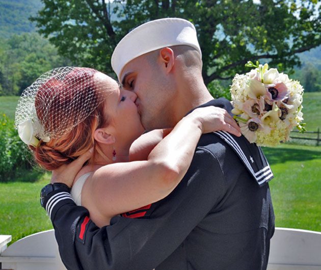 Bride and sailor groom kissing outdoors