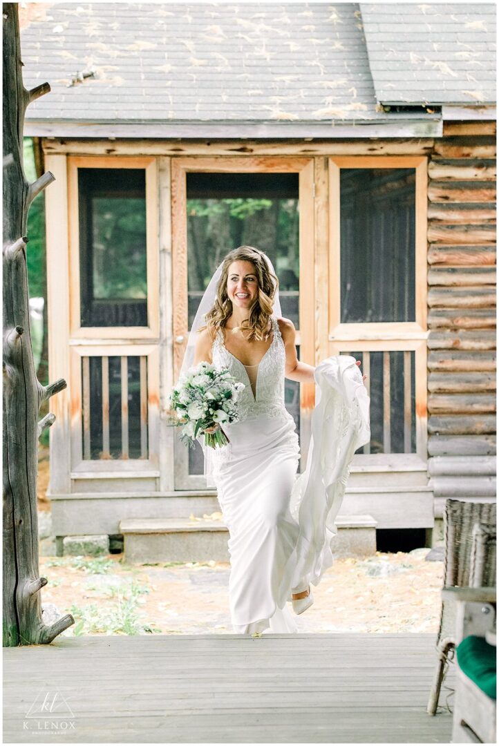 Bride in white gown holding bouquet by cabin