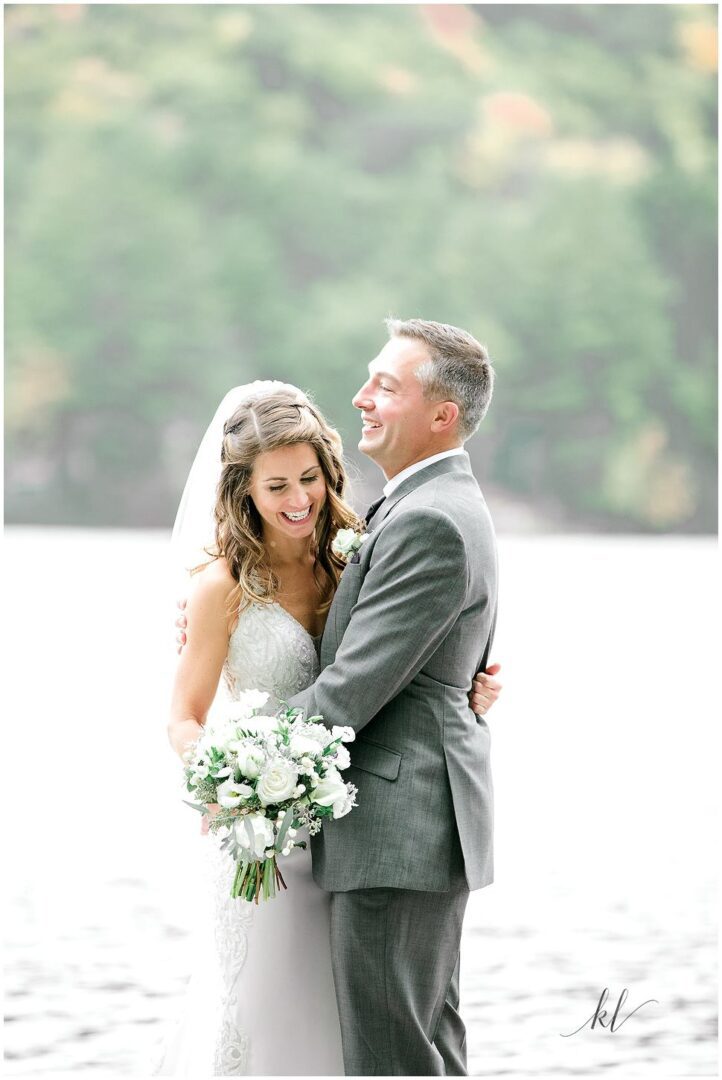 Bride and groom embracing by the lake